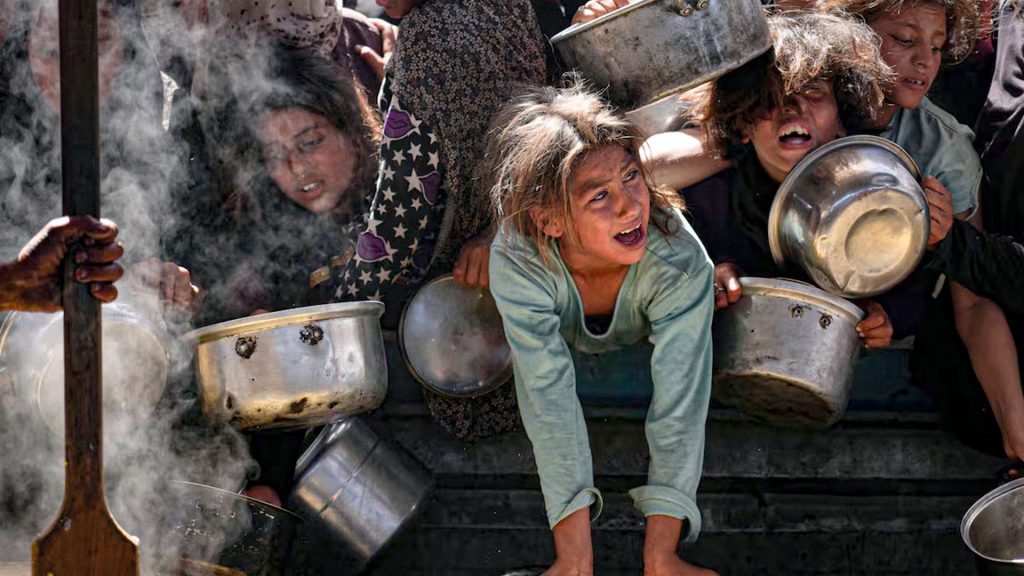Niños palestinos esperan comida en un comedor comunitario de Gaza durante la crisis alimentaria.